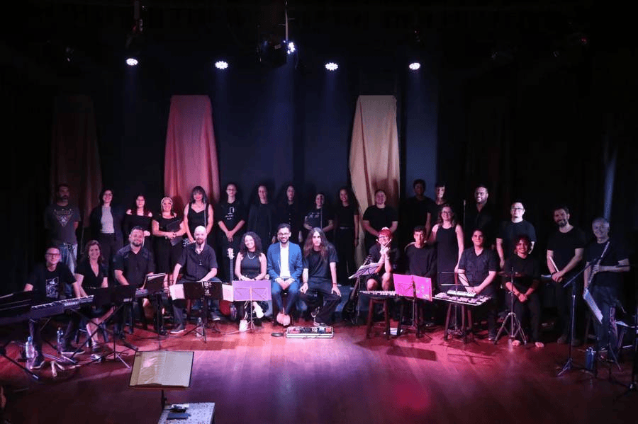 Canto coral e orquestra de instrumentos no palco do teatro.