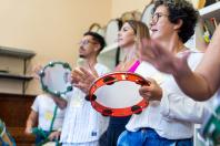 Várias pessoas tocando pandeiro em uma sala.