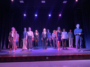 Vários jovens em um palco de teatro, todos de frente para o público.