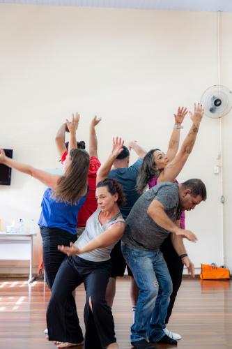 Seis pessoas juntas com as mãos para cima, de costas um para o outro.