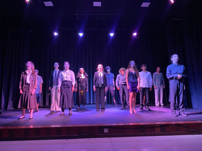 Vários jovens em um palco de teatro, todos de frente para o público.