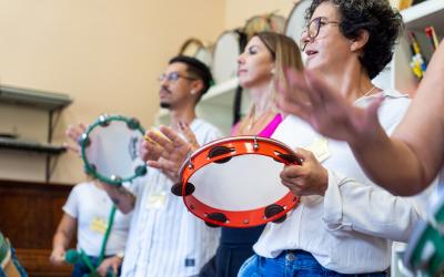 Várias pessoas tocando pandeiro em uma sala.